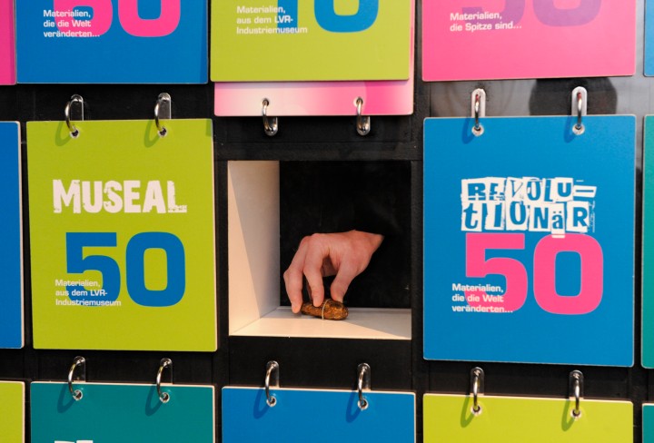 Eine Hand greift in einen Kasten in einer Wand mit Klappkisten
