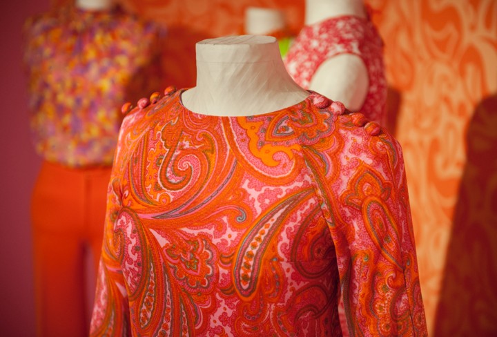 Orange-bunte Kleidung auf Büsten im Ausstellungsraum