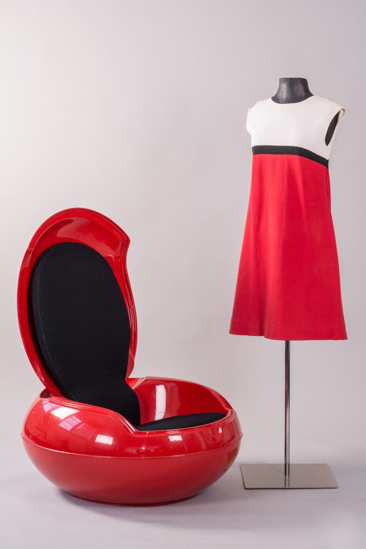 Foto zeigt ein rot-weißes Kleid an einer Figurine und einen roter Designsessel aus Kunststoff