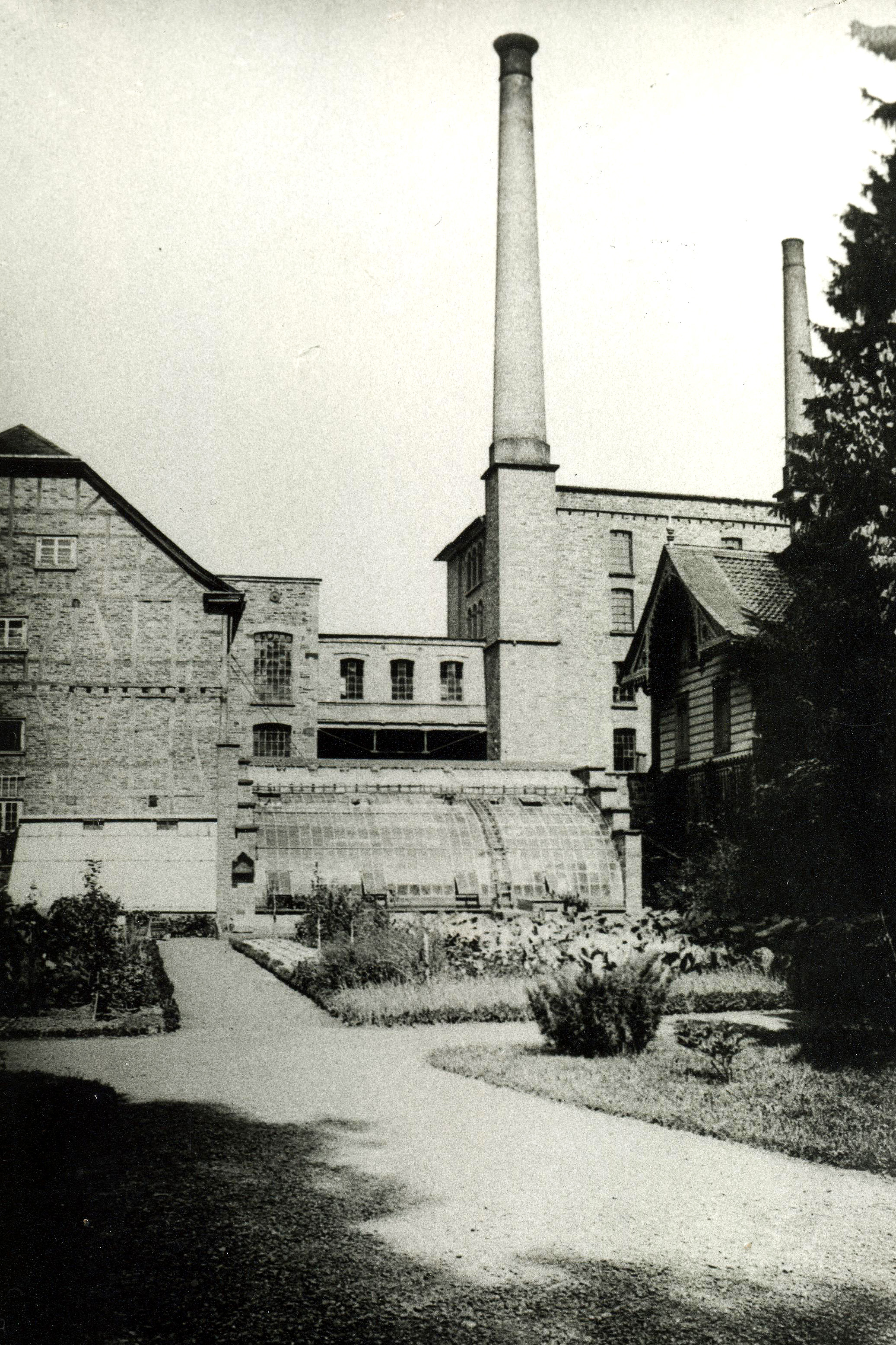 Historisches Schwarzweiß-Foto eines Gemüsebeets vor einer Fabrikanlage