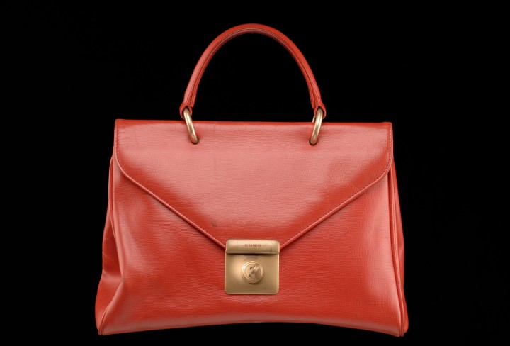 Rote Lack-Handtasche vor schwarzem Hintergund