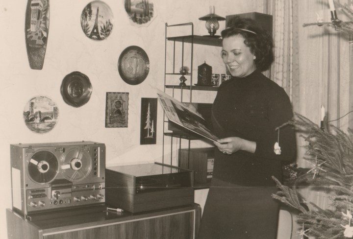 Foto zeigt ein schwarz-weiß Foto mit einer Frau vor einer alten Musiktruhe