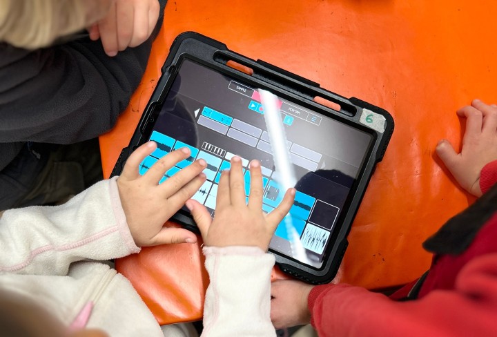 Foto von einem Tablet, was ein Mädchen bedient. Das Mädchen erstellt dort Musik.