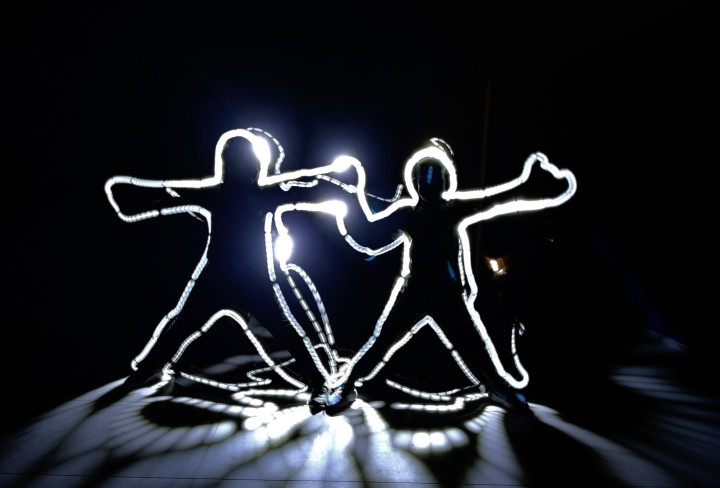 Es sind zwei menschliche Figuren zu sehen, die mit Licht beleuchtet werden.