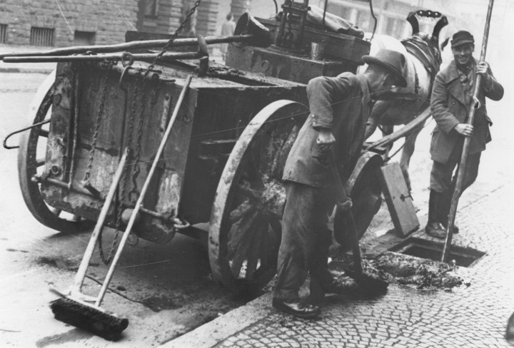 Historisches schwarz/weiß Foto mit Pferdefuhrwerk und Kanalarbeiter die die Straße fegen