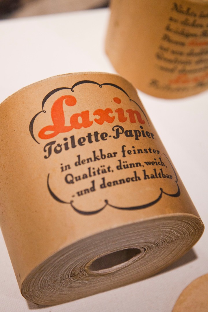 Foto zeigt eine Rolle Toilettepapier umwickelt in einem braunem Papier mit roter alter Schrift
