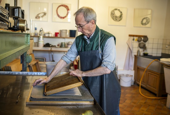 John Gerard beim Abgauschen eines frischgeschöpften Papierbogens