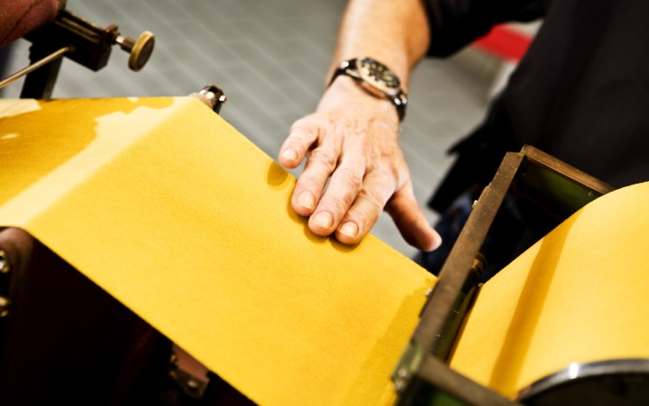 Detail view of a hand stroking yellow paper
