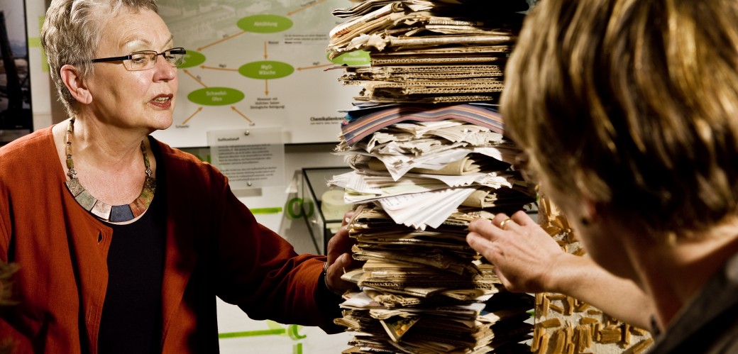 Women examine stacks of paper in the exhibition