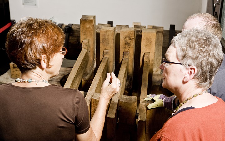 Zwei Damen und ein Herr an historischer Maschine in der ehemaligen Papiermühle