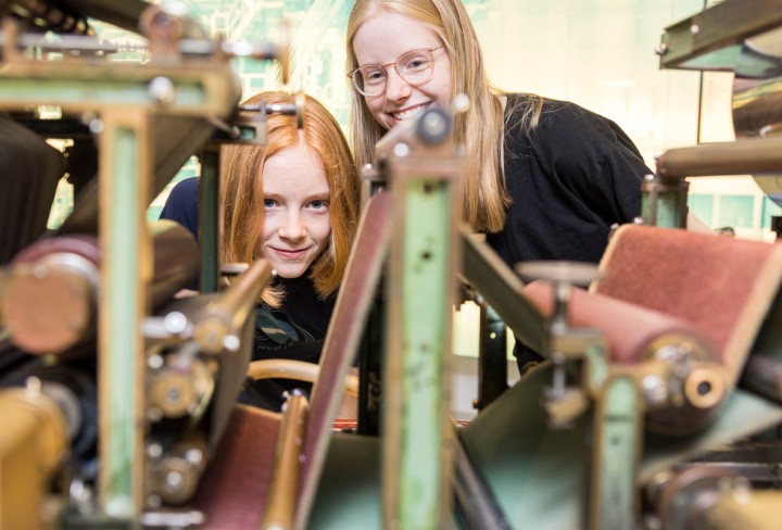 Zwei Mädchen betrachten eine große Papiermaschine