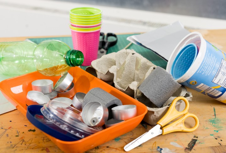 Verschiedene Bastelutensilien, unter anderem eine Schere, Plastikbecher und leere Teelichter.