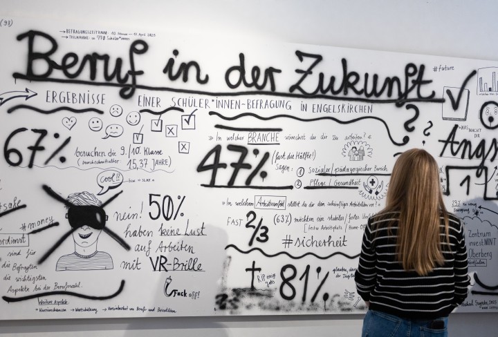 Eine Frau betrachtet eine selbstgestaltete Tafel zum Thema Beruf in der Zukunft.