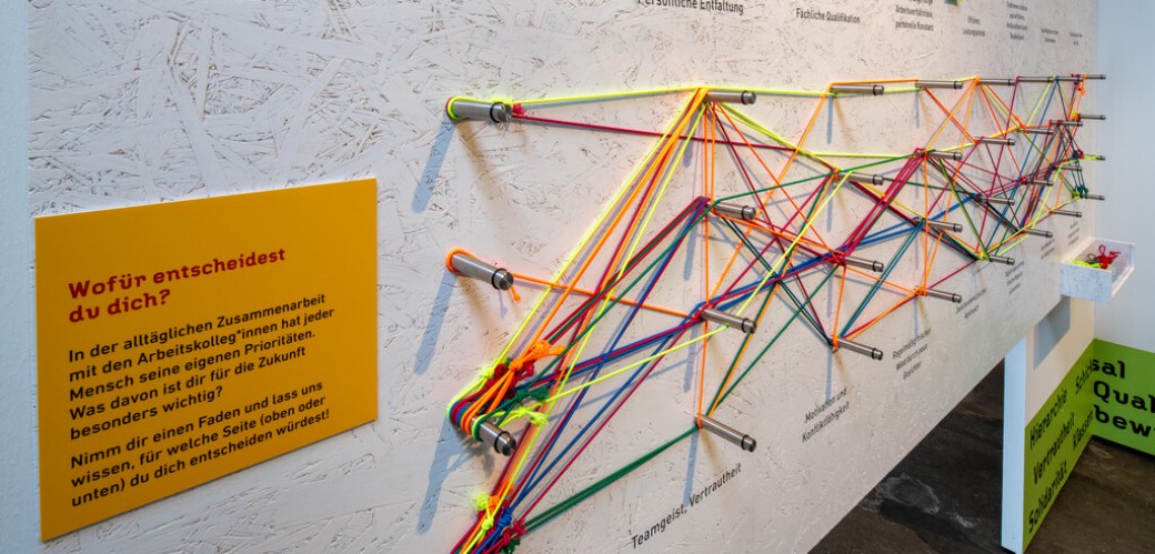 Eine Ausstellungswand mit vielen bunten Fäden