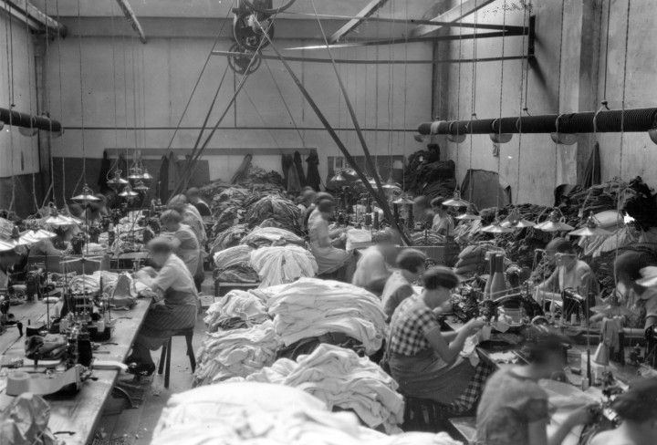 Textilfabrik mit Arbeitern die an Nähmaschinen arbeiten - in schwarzweiß