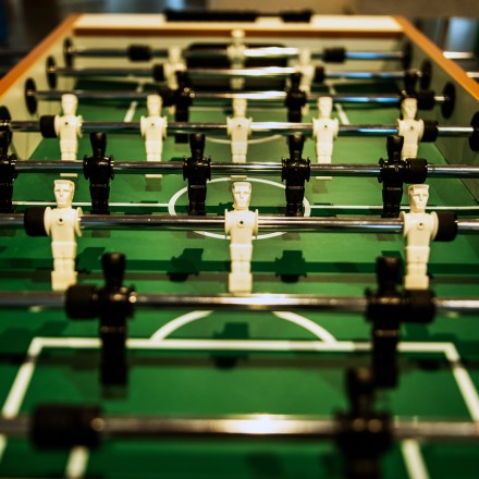 Das Foto zeigt die Spielfläche eines Fußballtisches mit schwarzen und weißen Figuren in Nahaufnahme.