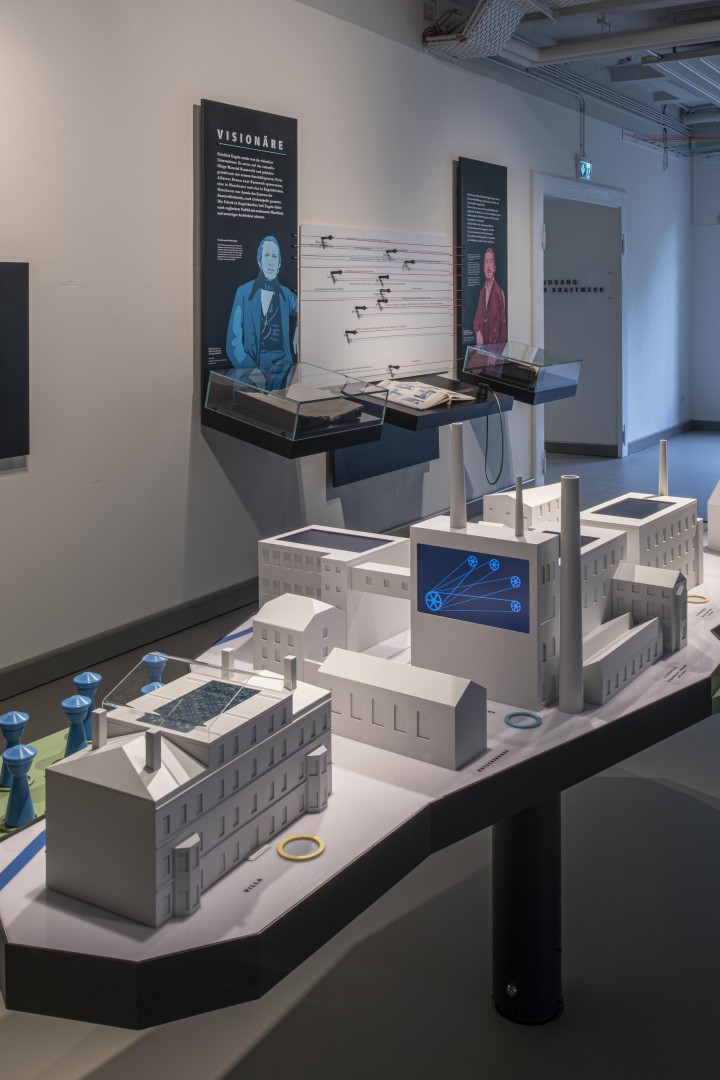 View of the exhibition with a factory model and information boards on the walls