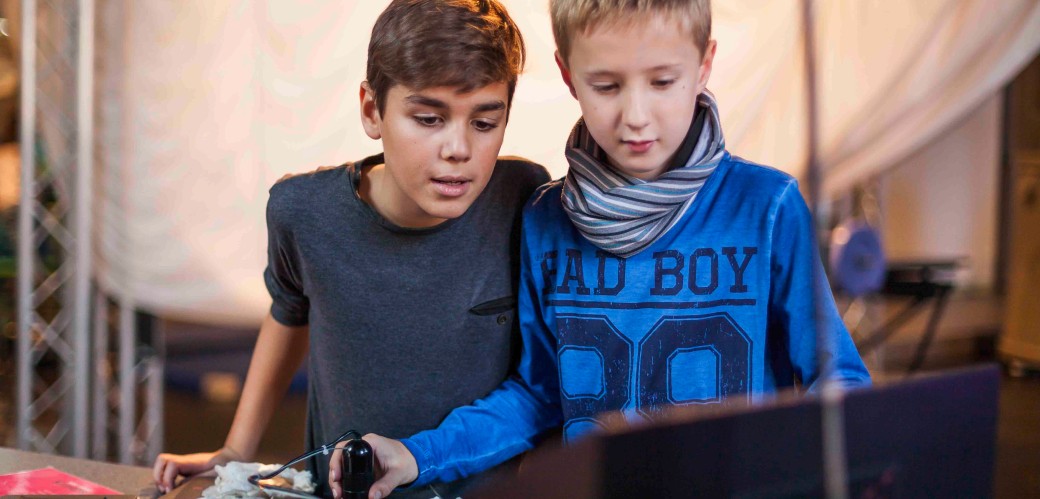 Zwei Jungen untersuchen ein Stück Stoff mit einer Mikroskop-Kamera