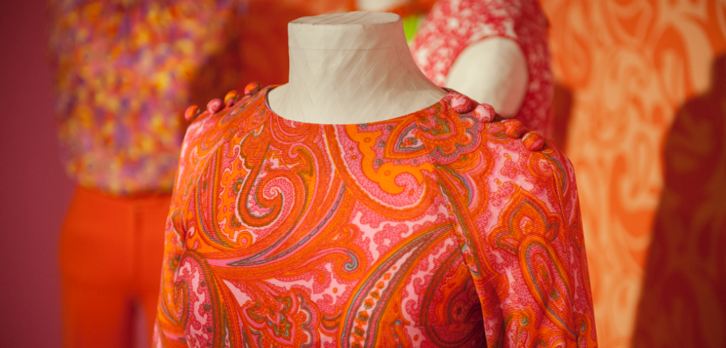 Kleid an einer Figurine. Das Kleid hat ein rot-orangenes Paisleymuster.