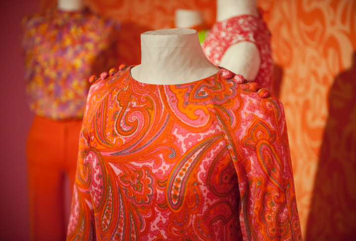 Orange-bunte Kleidung auf Büsten im Ausstellungsraum