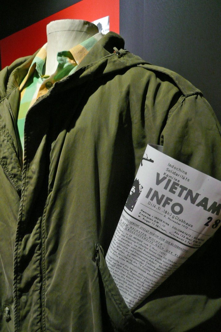 Foto zeigt eine grüne Jacke mit einer Zeitung in der Brusttasche