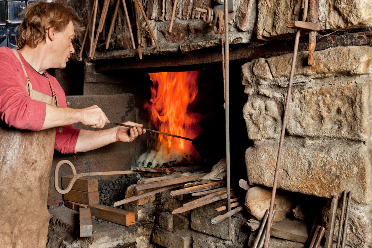 Museum blacksmith heats a workpiece in the furnace