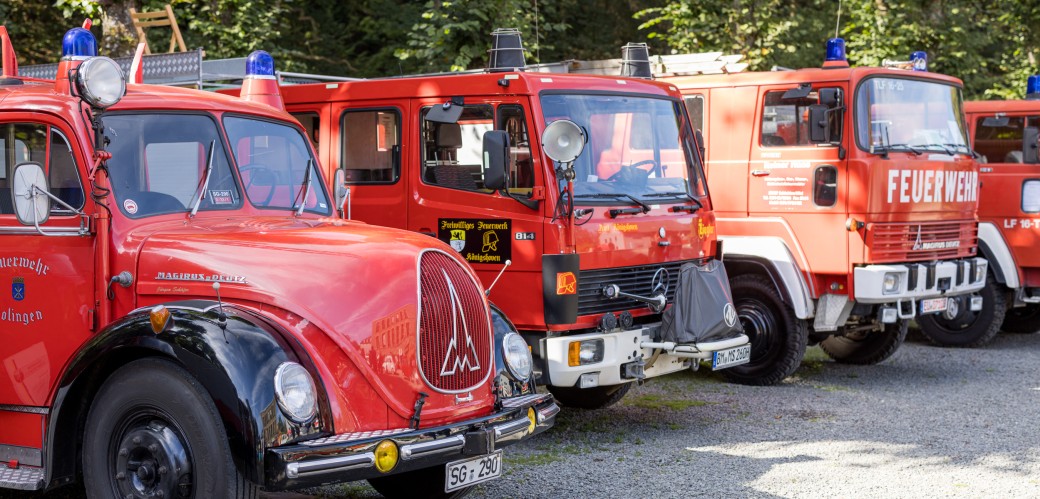 Das Foto zeigt vier historische Feuerwehrfahrzeuge, welche in einer Reihe aufgestellt sind.