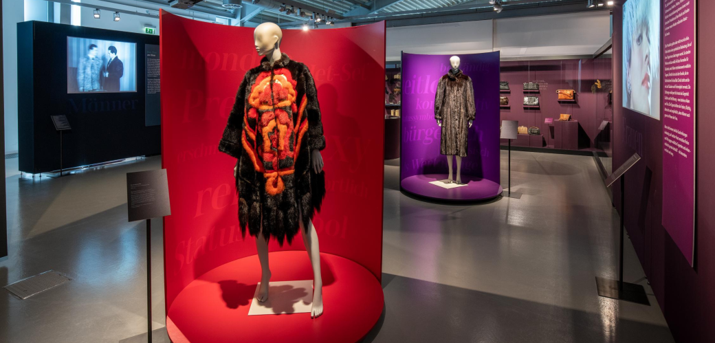 Blick in die Ausstellung "Modische Raubzüge" mit Nerzcape auf einem Mannequin im Vordergrund