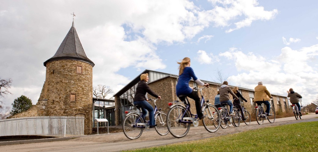 Erwachsene fahren Fahrrad vor dem Museumsgästehaus