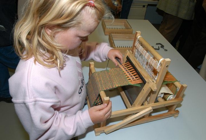 Girl weaves a miniature loom