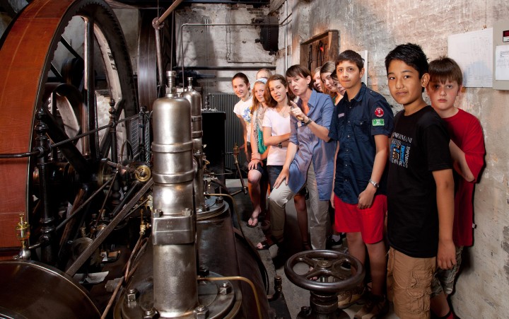 Schulklasse mit Museumspädagogin an historischer Dampfmaschine