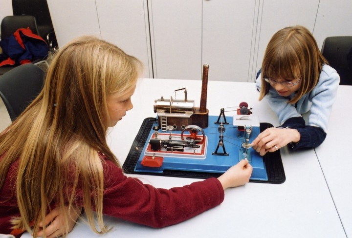 Kinder spielen am Modell einer Dampfmaschine