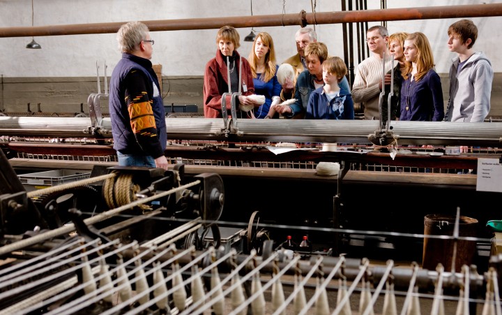 A group of adults watch a museum employee show a large machine