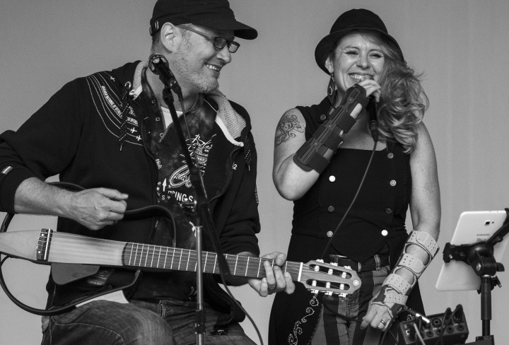 Schwarzweiß-Foto eines Manns mit Gitarre und einer Frau, die ins Mikrofon singt