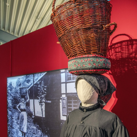 Schaufensterpuppe in historischer Kleidung mit einem Korb auf dem Kopf