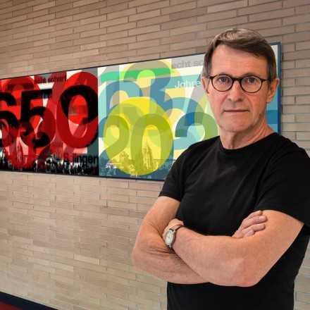 Das Bild zeigt den Künstler Ulli Steinküller vor einem seiner Werke.