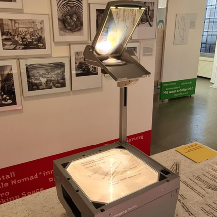 Overhead-Projektor vor einer Wand mit schwarz-weiß Aufnahmen