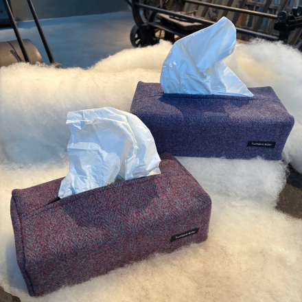 Drei karierte Kissen in knochenform liegen auf einem weißen Felluntergrund.