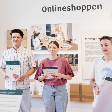 Drei junge Menschen stehen gegenüber von anderen jungen Menschen und halten jeweils eine Tafel in der Hand, auf der "Nein" steht und ein roter Daumen nach unten abgebildet ist.