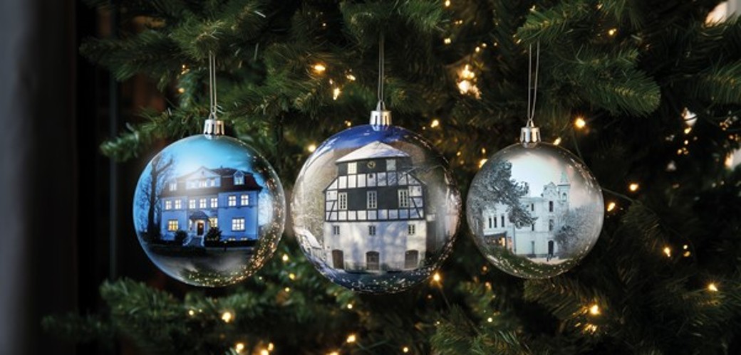 Weihnachtsmotiv mit drei Kugeln an einem Baum mit Lichterkette. Auf den drei Kugeln ist die Villa Altenberg, die Papiermühle Alte Dombach und die Villa hendrichs abgebildet. 