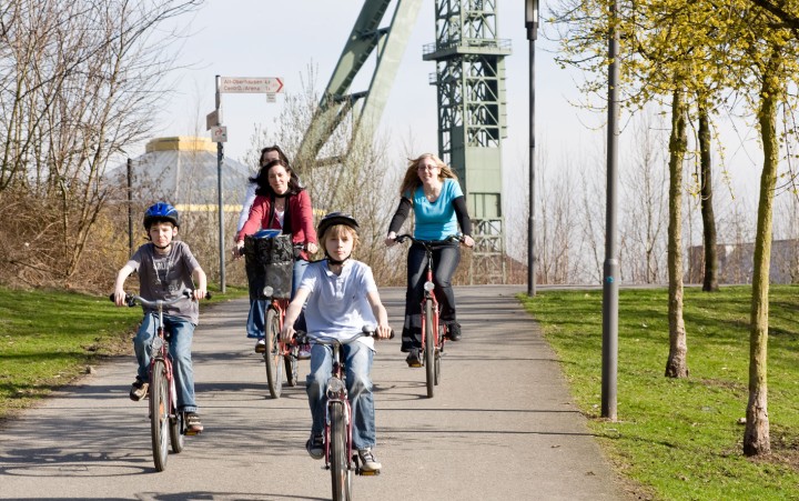 Adults and children on bicycles in front of a winding tower