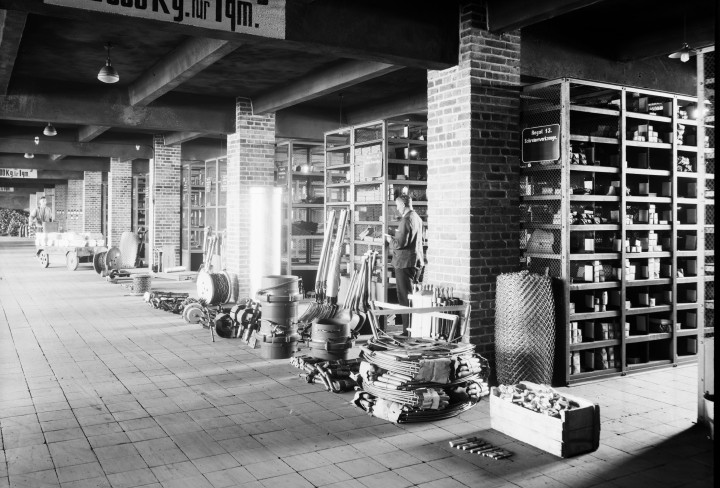 Ein schwarz-weiß Foto in einem Lager mit vielen vollen Regalreihen.