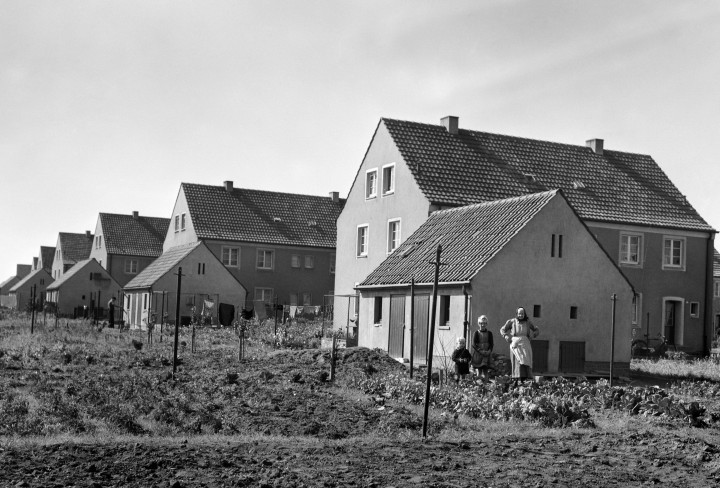 Schwarz-Weiß Foto zeigt Bergarbeitersiedlungshäuser mit einer Wiese davor 