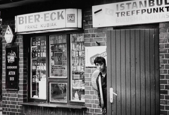 Schwarz-Weiß Foto zeigt einen jungen Mann vor einer Verkaufsbude