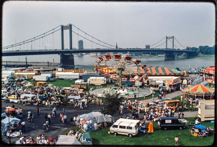 Flohmarkt auf der Mühlenweide in Duisburg in der Mitte der 1980er Jahre. Im Hintergrund sieht man den Rhein und am Horizont eine große Brücke.