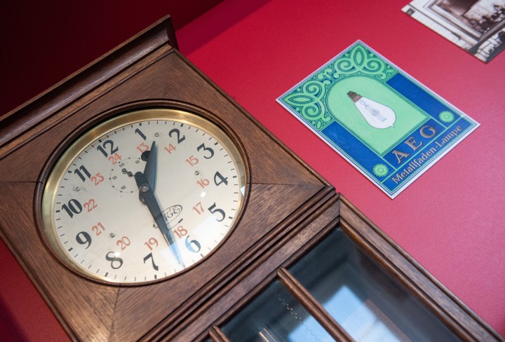 Eine Uhr und ein Logo von AEG an einer roten Wand in einer Ausstellung