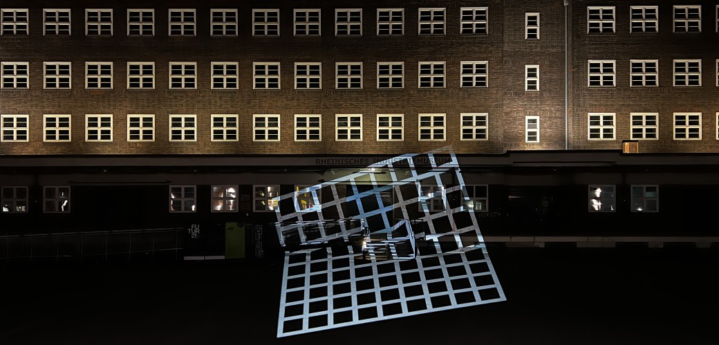 Großes, beleuchtetes Industriegebäude bei Nacht mit gitterförmiger Lichtinstallation