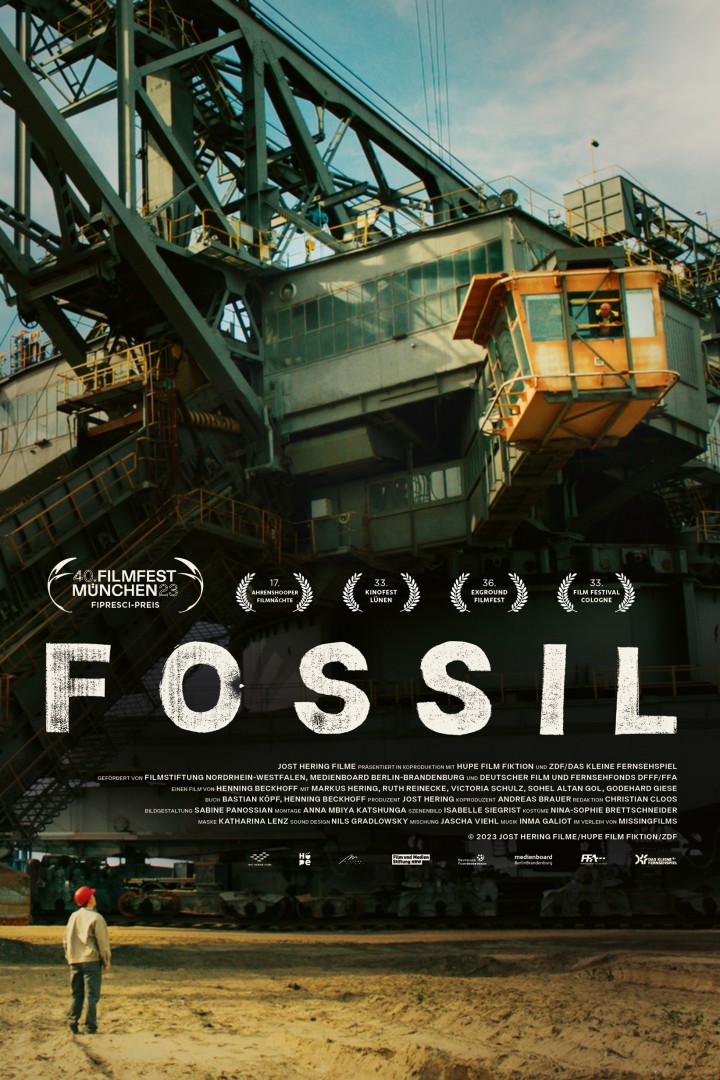 Plakat des Films "Fossil" mit einer Person mit Schutzhelm, die vor einem Braunkohlebagger steht. 