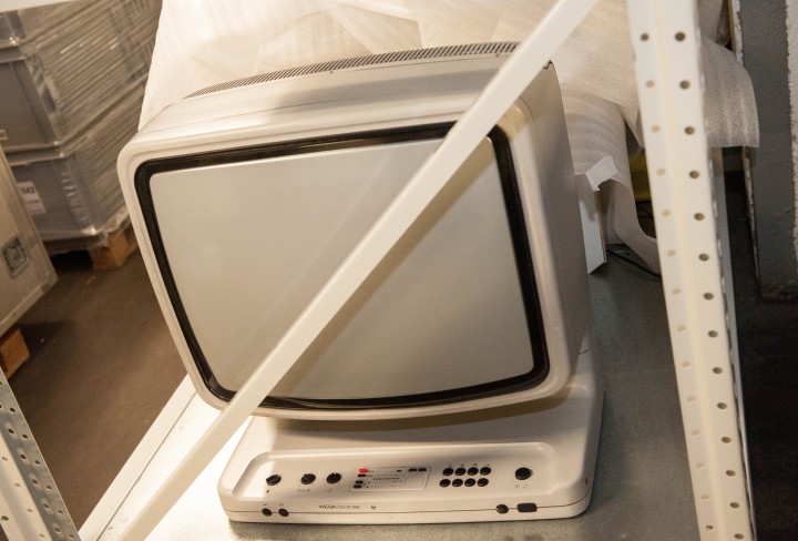 Ein weißer alter Fernseher steht in einem Stahlregal