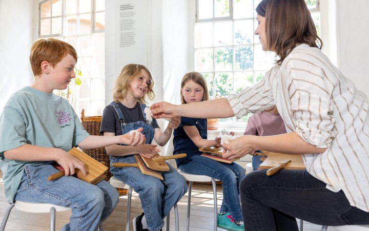 Eine Frau zeigt einer Gruppe Kindern Baumwollfasern